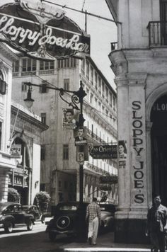 an old black and white photo of people walking down the street in front of shops