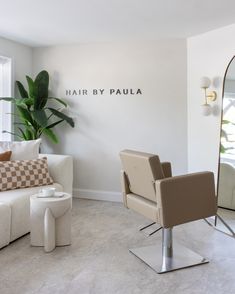 a chair and mirror in a room with a plant on the wall next to it