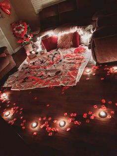 a living room filled with lots of red flowers and candles on the floor next to a couch