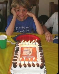 a young boy sitting in front of a birthday cake