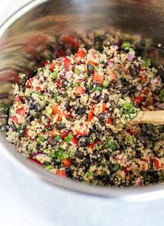 a bowl filled with rice, black beans and veggies next to a wooden spoon