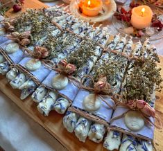 an arrangement of dried herbs and cookies on a table with lit candles in the background