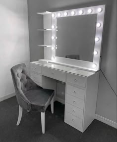 a white vanity with lights on it and a gray chair in front of the mirror