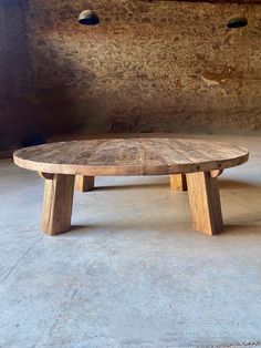 a wooden table sitting on top of a cement floor next to two lights hanging from the ceiling