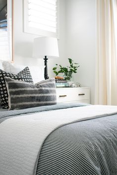 a bedroom with white walls and black and white bedding