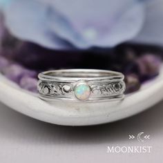 a white gold ring with an opalite in the center on a purple flower