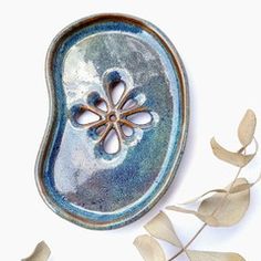 a blue and white dish sitting on top of a table next to some plants with leaves