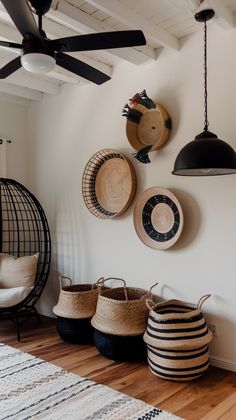 several baskets are hanging on the wall in a room with white walls and wooden floors