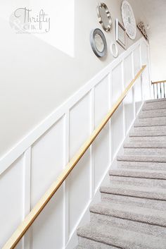 the stairs are lined with white carpet and wooden handrails, along with pictures on the wall