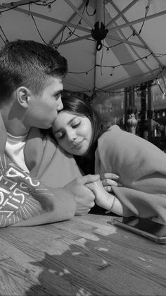 a young man and woman cuddle under an umbrella