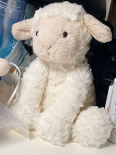 a white stuffed sheep sitting on top of a table