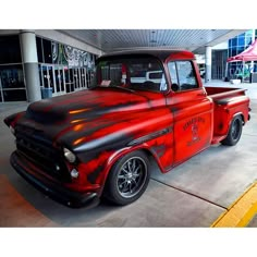 an old red truck parked in front of a building