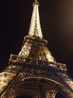 the eiffel tower lit up at night with lights on it's sides