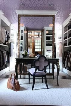 a chair and table in a room with closets full of clothes on the walls