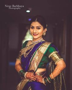 a woman in a green and gold sari with her hands on her hips, posing for