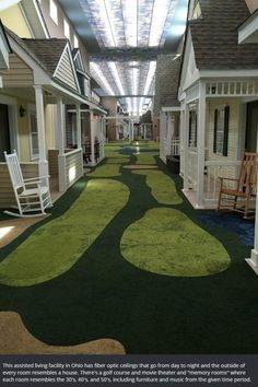 the inside of a building with green grass on the floor and white rocking chairs in the hallway