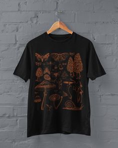 Thanks for stopping by! Moths and Mushrooms T-shirt Printed on a super soft, cotton tee Dispatched in 5 working days or sooner Unisex Free UK delivery Material: 100% ringspun cotton. Chest (to fit): S  34/36   M  38   L  40/42   XL  44/46   XXL  48/50 ECO-FRIENDLY Each garment is made to order, reducing extra material and energy that would be otherwise wasted We use DTG printing process which is easier on the environment than screen-printing Our ink is bright and also eco-friendly. Do not tumble Fairy Grunge Crew Neck T-shirt With Graphic Print, Fairy Grunge Graphic T-shirt For Summer, Fairy Grunge Short Sleeve Top With Screen Print, Fairy Grunge Crew Neck T-shirt With Screen Print, Black Short Sleeve Top With Mushroom Print, Fairy Grunge Graphic Print Crew Neck T-shirt, Goblincore Streetwear Crew Neck Tops, Goblincore Crew Neck Streetwear Tops, Fairycore Graphic Print Short Sleeve T-shirt