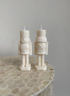 two white candles sitting on top of a table