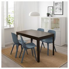 a dining room table with blue chairs in front of a white wall and rug on the floor