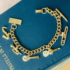 a blue book with a gold chain bracelet on it and some charms attached to it