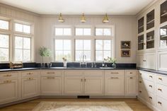 a large kitchen with white cabinets and black counter tops, along with an area rug on the floor