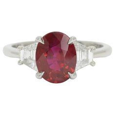 The Beaumont natural ruby engagement ring is centered by a vivid, pigeon blood red oval ruby certified by the Gemological Institute of America. A classic, 3 stone platinum mount featuring elegant claw prongs is accented by a pair of dazzling trapezoid shape diamonds and sits low on your hand for everyday enjoyment. This amazing gemstone bridal design is quite captivating given the glowing, fiery color of this modern treasure.   Condition: New Era: Classical Year: 2021 Metal: Platinum Center Gems Luxury Oval Three-stone Ruby Ring, Classic Red Ruby Ring With Vvs Clarity, Luxury Three Stone Ruby Ring, Classic Red Three Stone Rings, Oval Red Ruby Ring With Three Stones, Oval Ruby Ring With Three Diamonds, Oval Three Stone Ruby Ring With Diamonds, Formal Red Ruby Ring With Three Stones, Formal Ruby Three Stone Ring