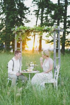 a man and woman sitting at a table in the grass