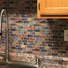 a kitchen sink under a faucet in front of a tiled backsplash