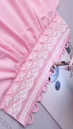 a pink umbrella with white lace on it being cut by a pair of pliers