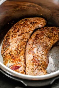 two pieces of meat in a pot with some seasoning on top of the meat