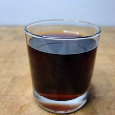 a glass filled with liquid sitting on top of a wooden table