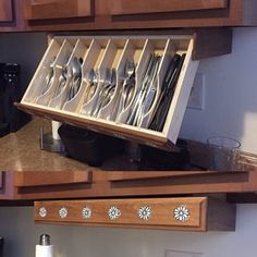 an open drawer with utensils in it on top of a kitchen countertop