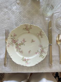 a white plate with pink flowers on it next to silverware and utensils