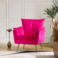 a bright pink chair sitting next to a potted plant