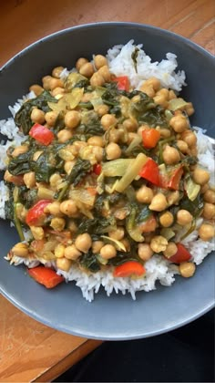 a blue bowl filled with white rice and chickpeas on top of it next to a wooden table