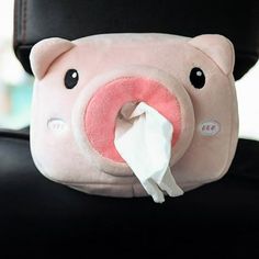 a pink stuffed pig with a tissue roll in its mouth sitting on a black chair