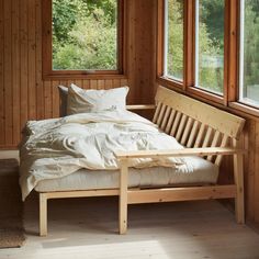 a bed sitting in the middle of a room next to two windows with wooden frames