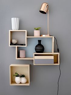 some shelves with vases and other items on them against a gray wall in a living room