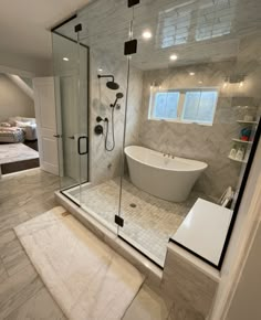 a bathroom with a large tub and walk in shower next to a white rug on the floor