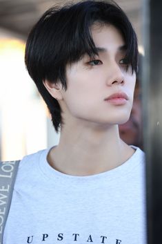 a young man with black hair wearing a gray shirt