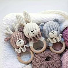 three crocheted stuffed animals laying next to each other on top of some balls of yarn