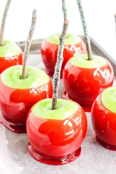 red and green apples with sticks sticking out of them