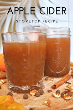 two glasses filled with apple cider sitting on top of a wooden table