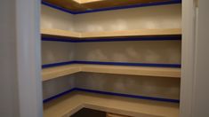 an empty closet with blue tape on the walls and shelves lined up against the wall