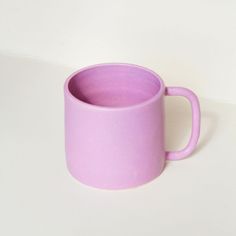 a pink coffee cup sitting on top of a white table