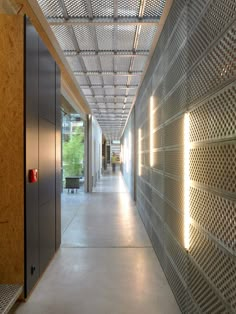 an empty hallway is lit up with lights and perfored metal screens on the walls