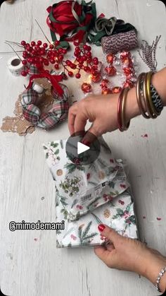 a woman is making christmas decorations on the floor with her hands and sewing supplies in front of her