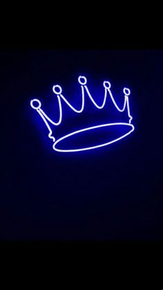 a blue neon sign with a crown on it's side in the dark,