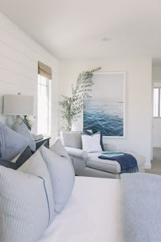 a living room filled with white furniture and blue pillows on top of it's couches