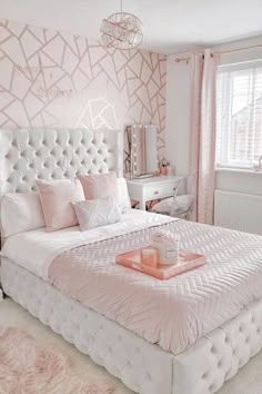 a white bed sitting in a bedroom next to a dresser and mirror on top of a wall